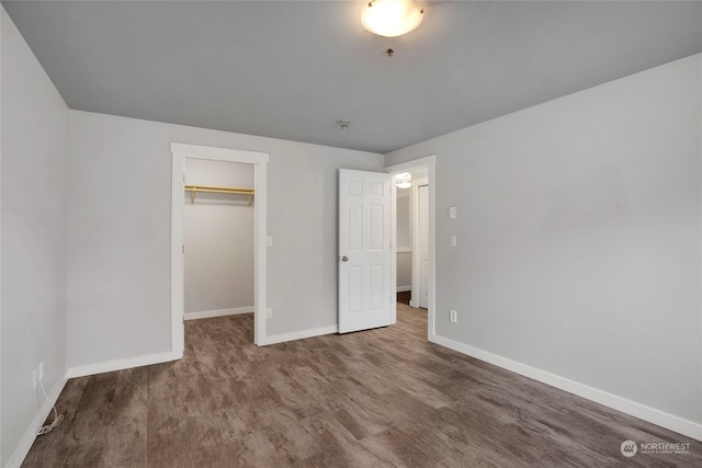 unfurnished bedroom with hardwood / wood-style floors, a spacious closet, and a closet