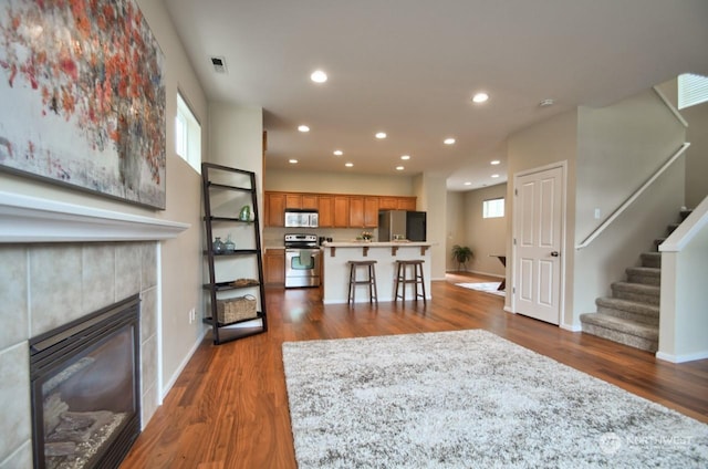 living room featuring a tile fireplace, dark hardwood / wood-style floors, and a healthy amount of sunlight