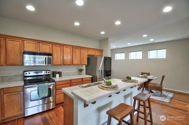 kitchen featuring tile countertops, sink, a kitchen breakfast bar, a center island, and stainless steel appliances