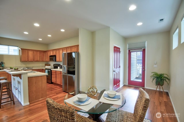 kitchen featuring sink, stainless steel appliances, a kitchen breakfast bar, a kitchen island, and light wood-type flooring