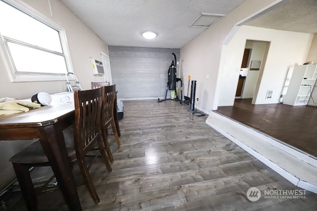 dining room featuring hardwood / wood-style floors, a textured ceiling, and a wall unit AC