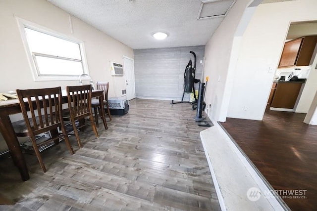 dining space with hardwood / wood-style floors, a wall mounted air conditioner, and a textured ceiling