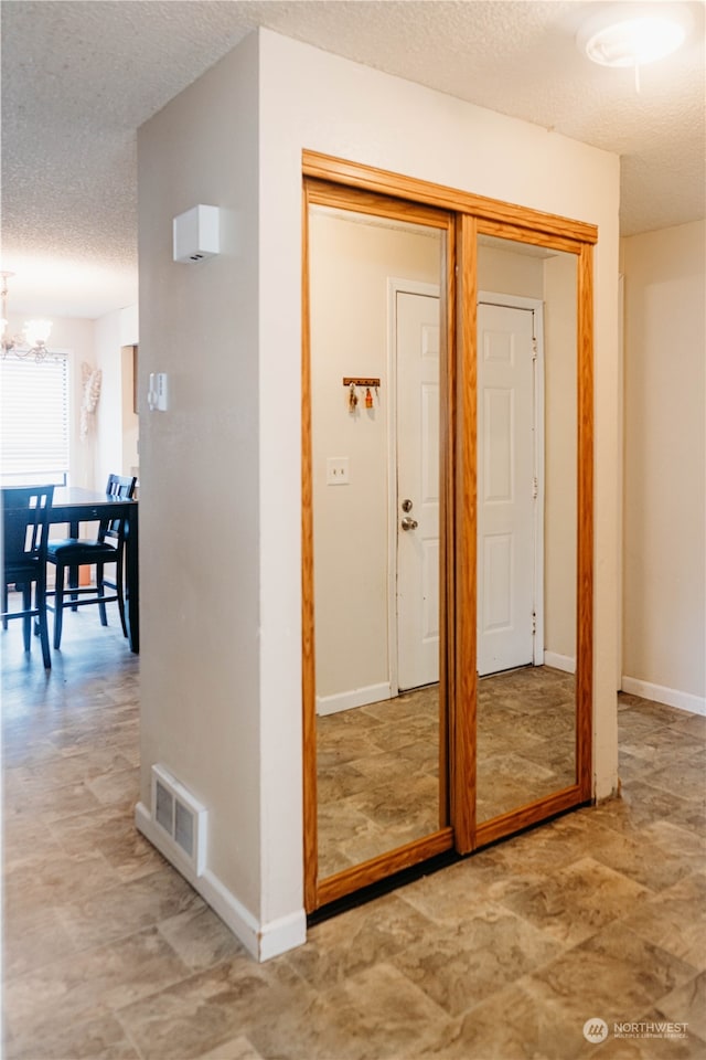 hallway with a chandelier and a textured ceiling