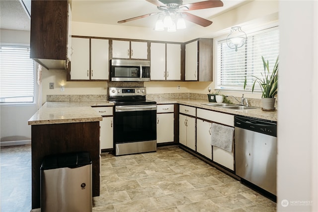 kitchen with appliances with stainless steel finishes, white cabinetry, ceiling fan, and sink