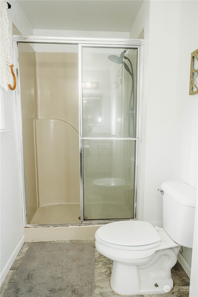 bathroom featuring toilet and a shower with door