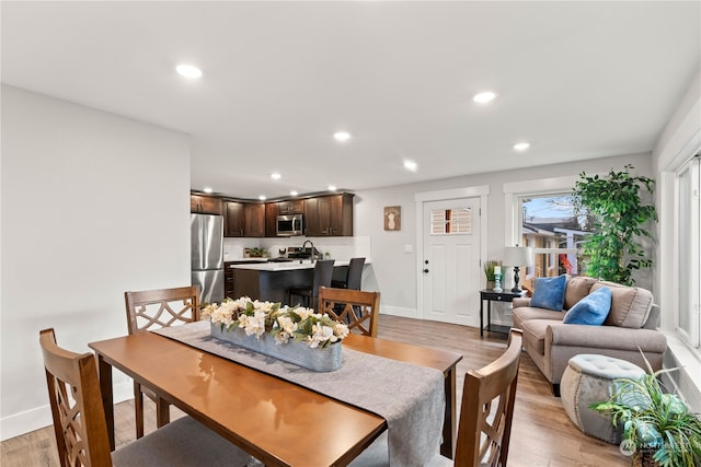 dining space with sink and light wood-type flooring