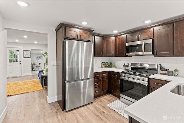 kitchen featuring appliances with stainless steel finishes, backsplash, light hardwood / wood-style floors, and dark brown cabinets