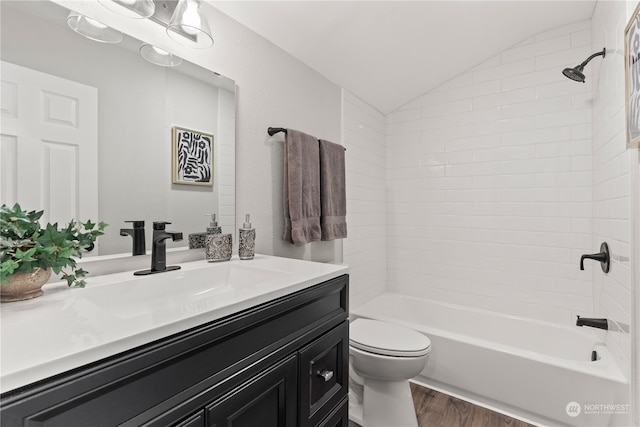 full bathroom featuring vanity, tiled shower / bath combo, vaulted ceiling, hardwood / wood-style flooring, and toilet