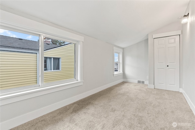 empty room featuring carpet and lofted ceiling