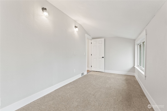 spare room featuring carpet and lofted ceiling