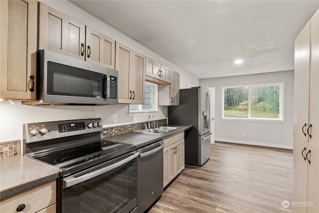 kitchen with light brown cabinetry, sink, appliances with stainless steel finishes, and light hardwood / wood-style flooring