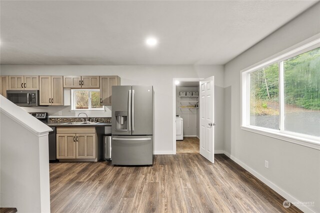 kitchen featuring sink, light brown cabinetry, appliances with stainless steel finishes, dark hardwood / wood-style flooring, and washer / clothes dryer