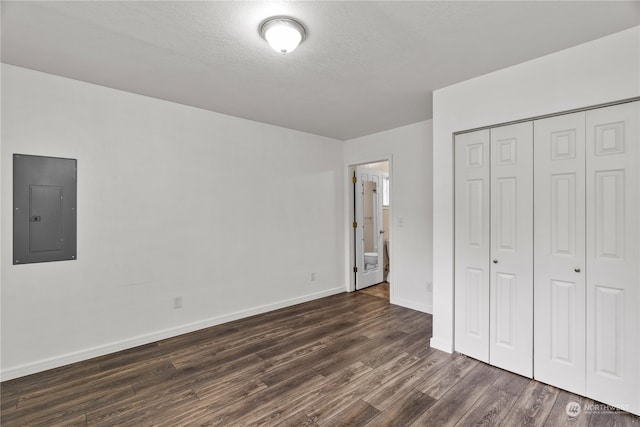 unfurnished bedroom featuring dark hardwood / wood-style floors, a textured ceiling, electric panel, and a closet