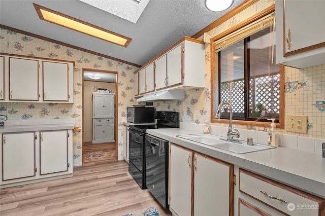 kitchen with sink, white cabinetry, black appliances, and vaulted ceiling with skylight