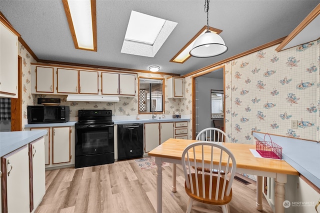 kitchen with black appliances, white cabinets, hanging light fixtures, a textured ceiling, and light hardwood / wood-style floors