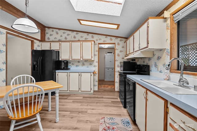 kitchen featuring white cabinets, pendant lighting, vaulted ceiling with skylight, and black appliances