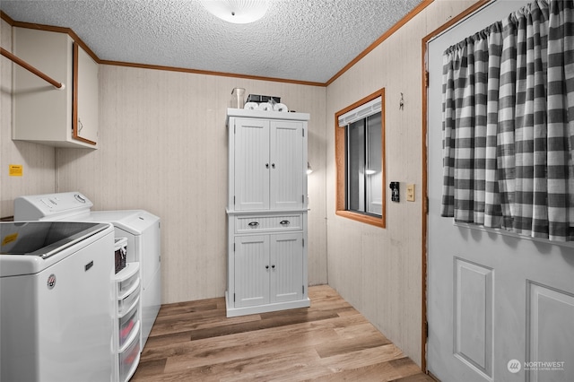 laundry area featuring washing machine and clothes dryer, light hardwood / wood-style flooring, cabinets, and ornamental molding