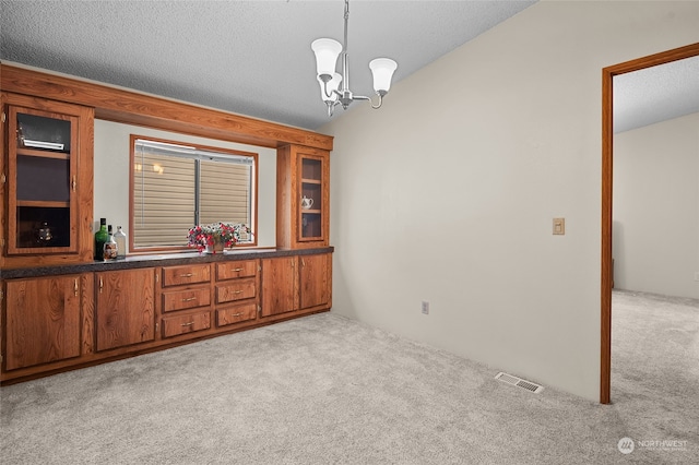 unfurnished dining area featuring a textured ceiling, a notable chandelier, and light carpet