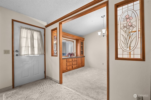 entrance foyer with a textured ceiling, light colored carpet, and an inviting chandelier