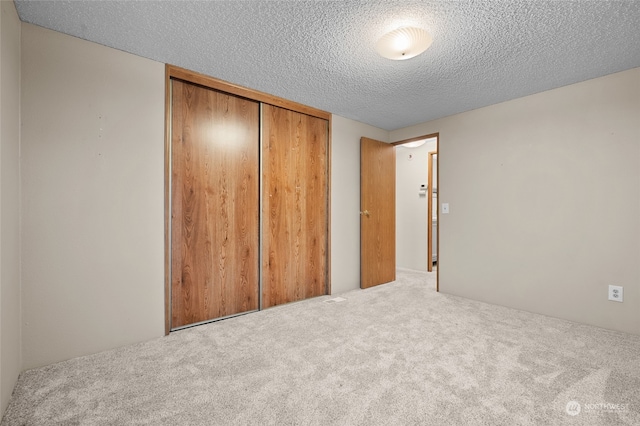 unfurnished bedroom featuring carpet flooring, a textured ceiling, and a closet