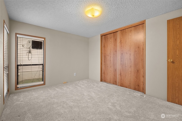 unfurnished bedroom featuring a closet, carpet floors, and a textured ceiling