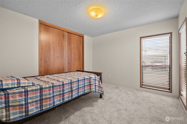 carpeted bedroom featuring a textured ceiling and a closet