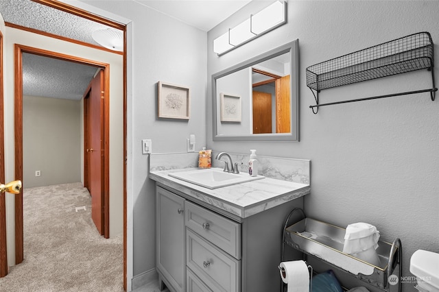 bathroom with vanity, toilet, and a textured ceiling