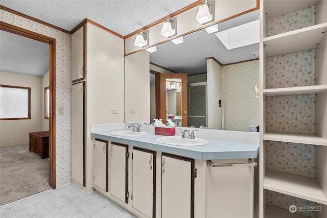 bathroom featuring vanity, a textured ceiling, a skylight, and ornamental molding