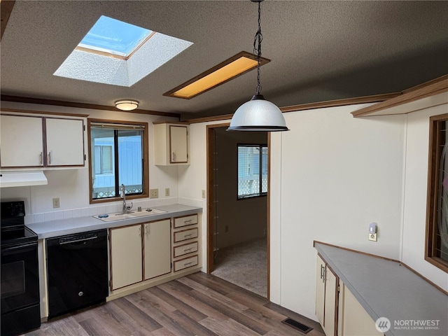 kitchen featuring visible vents, wood finished floors, a sink, black appliances, and a skylight