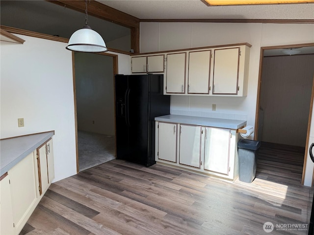 kitchen featuring decorative light fixtures, light countertops, lofted ceiling with beams, black refrigerator with ice dispenser, and light wood-style floors