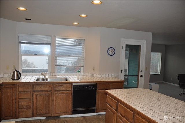 kitchen with tile patterned floors, sink, tile counters, and black dishwasher