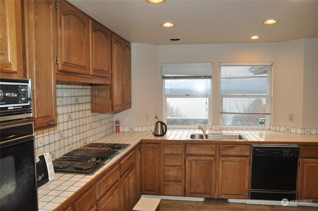 kitchen featuring sink, tasteful backsplash, tile counters, and black appliances