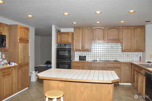 kitchen featuring a center island, backsplash, tile counters, and black appliances