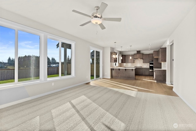 unfurnished living room with light wood-type flooring and ceiling fan