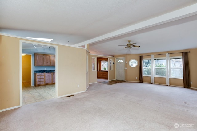 unfurnished living room with beam ceiling, light carpet, ceiling fan, and a skylight