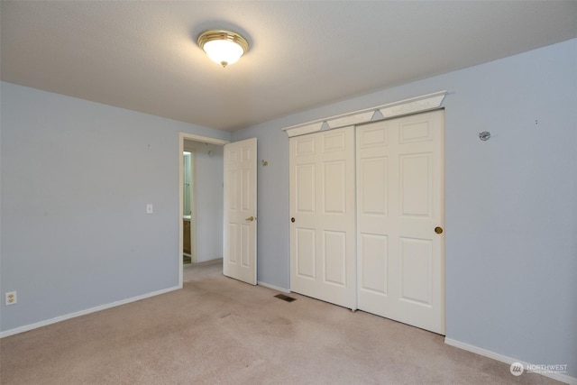 unfurnished bedroom with light colored carpet and a closet