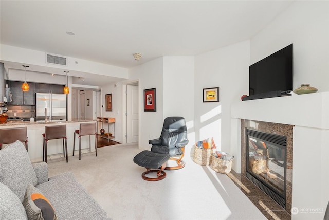 carpeted living room with a fireplace and sink