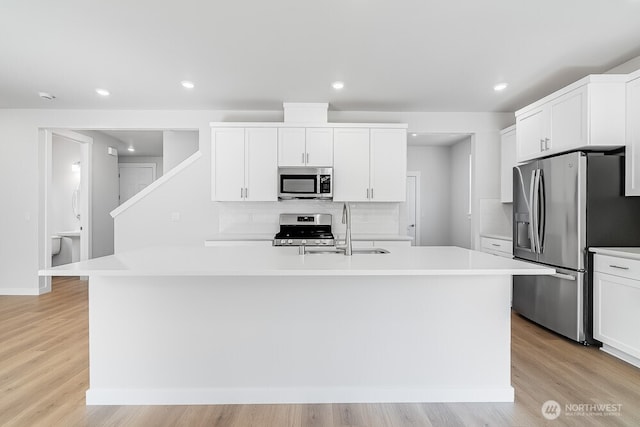 3313 SE 12th Ave, Battle Ground, WA 98604 - kitchen featuring stainless steel appliances, a center island with sink, light countertops, white cabinets, and light wood-style floors