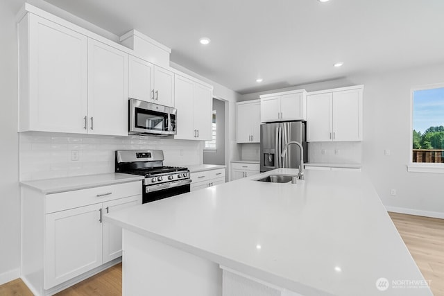 3313 SE 12th Ave, Battle Ground, WA 98604 - kitchen with stainless steel appliances, light countertops, white cabinetry, backsplash, and light wood finished floors
