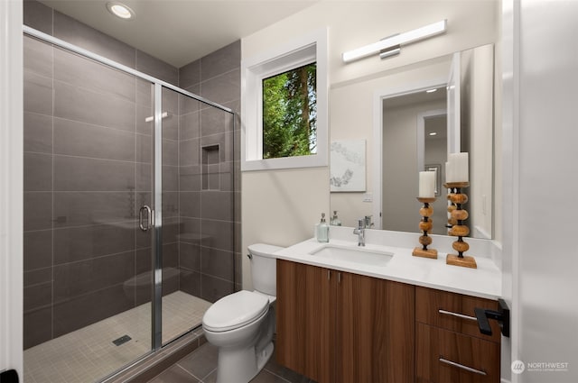 bathroom featuring tile patterned floors, vanity, a shower with shower door, and toilet