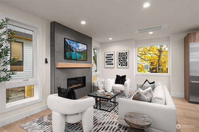 living room with a tile fireplace and light hardwood / wood-style flooring