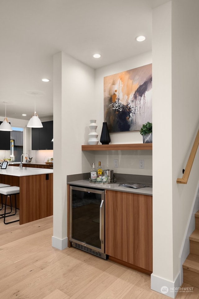 bar with wine cooler, sink, pendant lighting, and light wood-type flooring