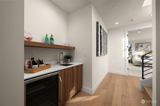 bar with light hardwood / wood-style floors, wine cooler, and sink