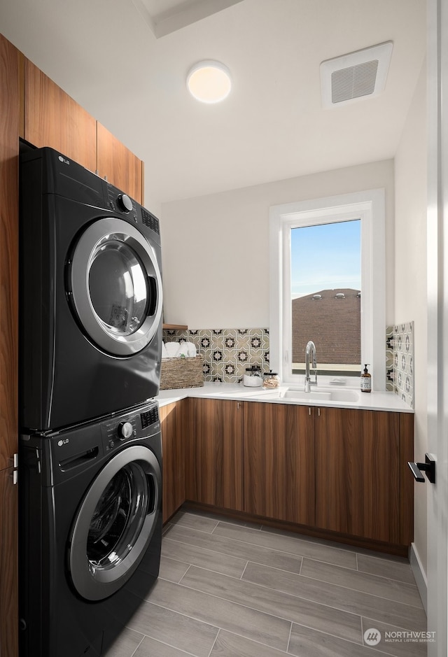 clothes washing area featuring stacked washer and dryer and sink