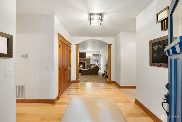 corridor with light hardwood / wood-style floors and decorative columns