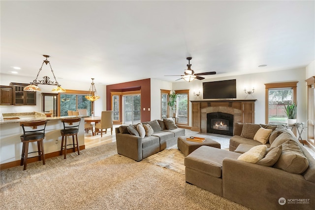 living room featuring a tile fireplace, ceiling fan, and carpet floors