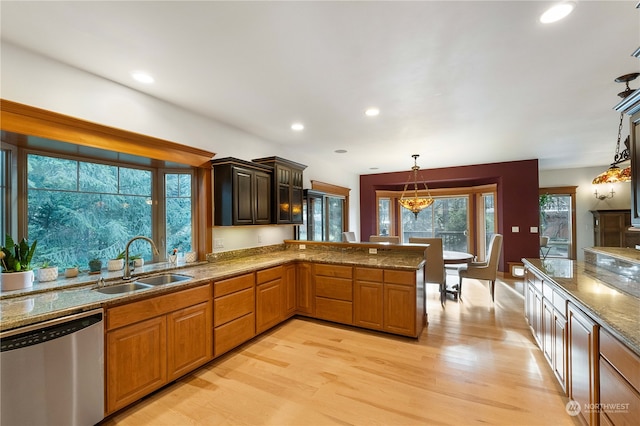 kitchen featuring pendant lighting, dishwasher, sink, light hardwood / wood-style floors, and kitchen peninsula