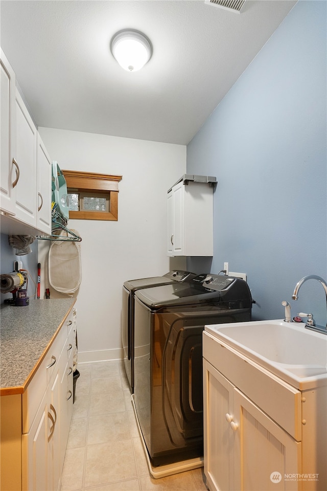 laundry area featuring light tile patterned flooring, cabinets, separate washer and dryer, and sink