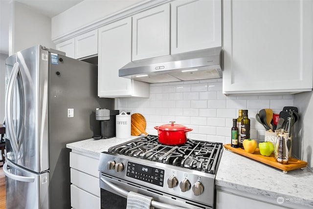 kitchen featuring white cabinets, stainless steel appliances, tasteful backsplash, and light stone countertops