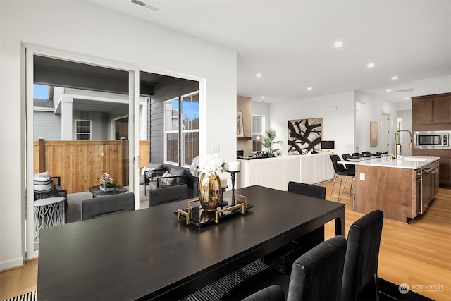 dining space with light wood-type flooring, sink, and a skylight